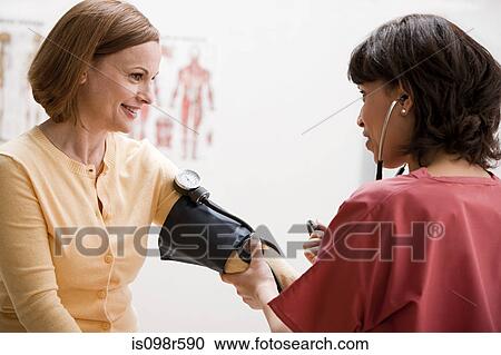 Stock Image - Woman having blood pressure tested. Fotosearch