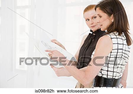 Stock Image - Fashion designers looking at sketches. Fotosearch