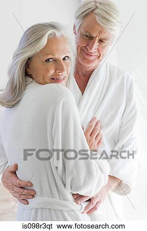 Stock Photograph - Middle aged couple in bathrobes hugging. Fotosearch