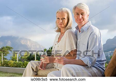 Stock Photography - Middle aged couple relaxing outside with glasses of wine. Fotosearch