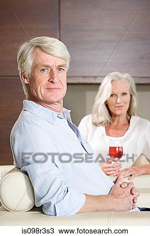 Stock Image - Middle aged couple relaxing with glass of wine. Fotosearch
