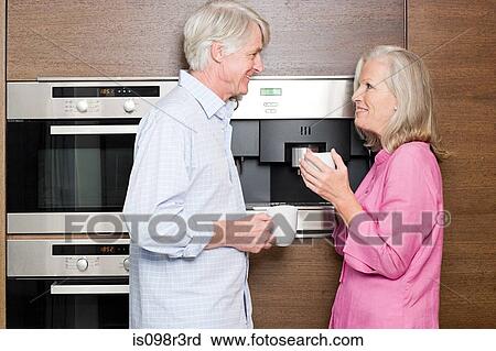Middle aged couple standing in kitchen with cups of coffee View Large Photo Image Stock Image - Middle aged couple standing in kitchen with cups of coffee. Fotosearch