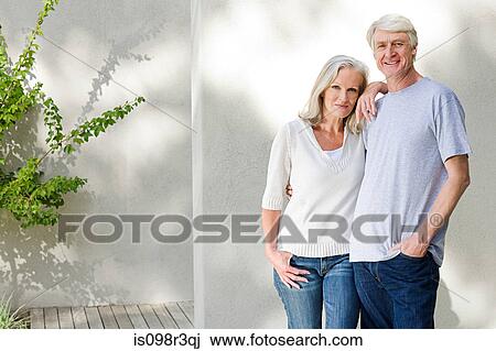 Stock Image - Middle aged couple standing outside on deck. Fotosearch