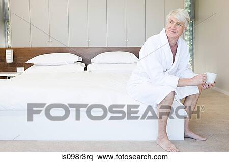 Middle aged man in bathrobe sitting on bed with cup of coffee View Large Photo Image Stock Photography - Middle aged man in bathrobe sitting on bed with cup of coffee. Fotosearch