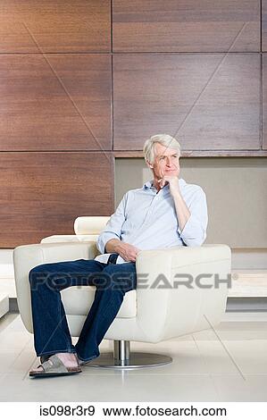 Thoughtful middle aged man sitting on modern armchair View Large Photo Image Stock Photo - Thoughtful middle aged man sitting on modern armchair. Fotosearch