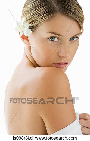 Stock Image - Portrait of young woman with bare shoulders and a frangipani in her hair. Fotosearch