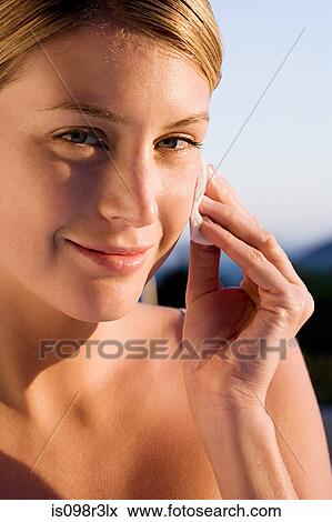 Young woman cleaning face with cotton pad View Large Photo Image Stock Photo - Young woman cleaning face with cotton pad. Fotosearch