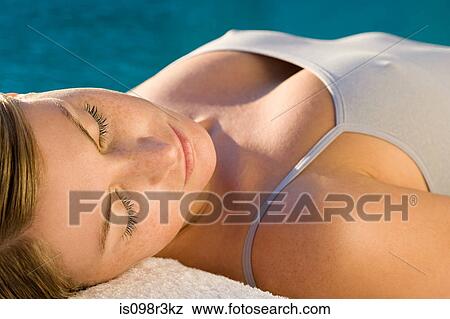 Stock Photo - Young woman lying on massage table by the pool. Fotosearch
