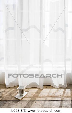 Stock Image - Coffee cup by net curtains. Fotosearch