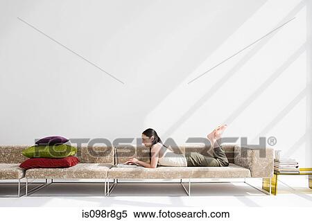 Stock Photography - Japanese woman relaxing on sofa. Fotosearch