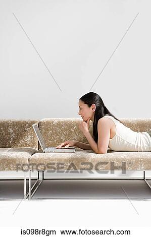Japanese woman using laptop computer on sofa View Large Photo Image Picture - Japanese woman using laptop computer on sofa. Fotosearch