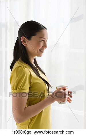 Smiling japanese woman standing at window View Large Photo Image Stock Photography - Smiling japanese woman standing at window. Fotosearch