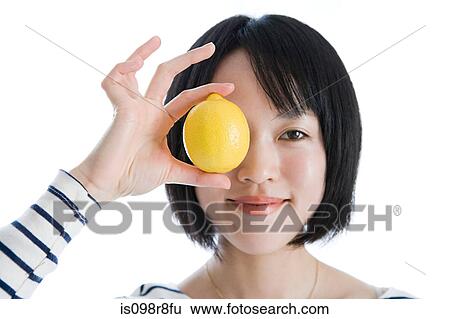 Stock Photograph - Woman holding a lemon to her eye. Fotosearch