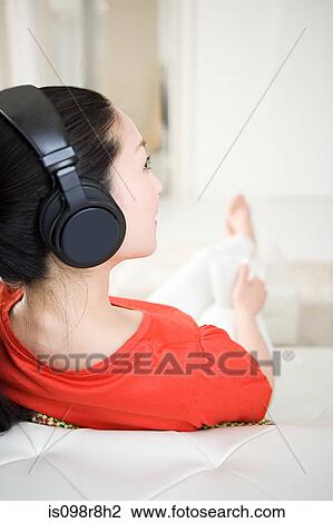 Woman listening to music on sofa View Large Photo Image Stock Image - Woman listening to music on sofa. Fotosearch
