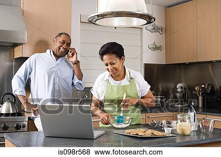 Couple in kitchen with laptop and cellphone View Large Photo Image Stock Photo - Couple in kitchen with laptop and cellphone. Fotosearch