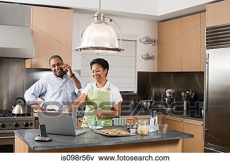 Couple in kitchen with laptop and cellphone View Large Photo Image Stock Photo - Couple in kitchen with laptop and cellphone. Fotosearch