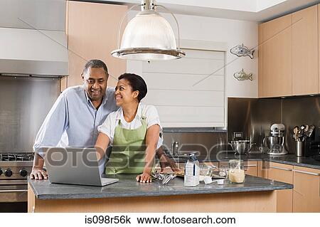 Couple in kitchen with laptop View Large Photo Image Stock Image - Couple in kitchen with laptop. Fotosearch