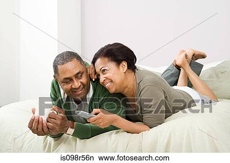 Couple watching television on bed View Large Photo Image Picture - Couple watching television on bed. Fotosearch
