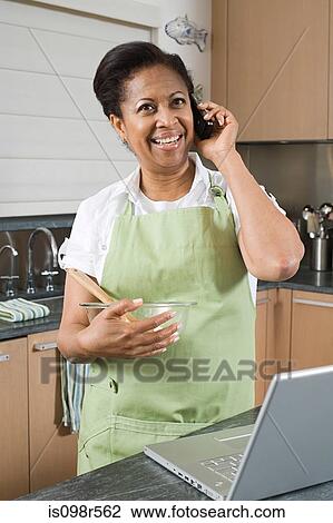 Woman in kitchen with laptop and cellphone View Large Photo Image Stock Image - Woman in kitchen with laptop and cellphone. Fotosearch