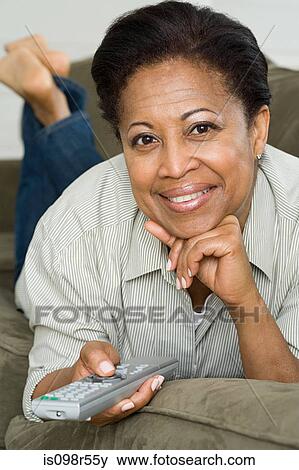 Woman on sofa with remote control View Large Photo Image Stock Photo - Woman on sofa with remote control. Fotosearch