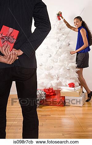 Man hiding a christmas gift behind back View Large Photo Image Stock Image - Man hiding a christmas gift behind back. Fotosearch