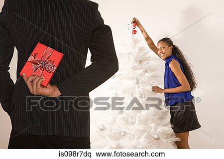 Stock Photography - Man hiding a christmas gift behind back. Fotosearch