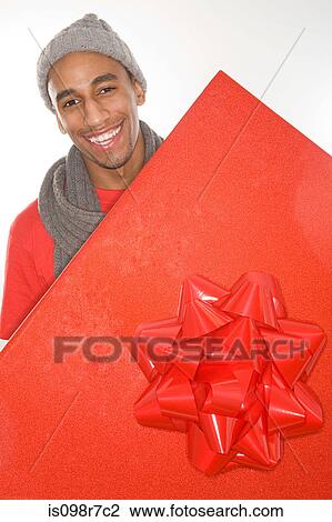 Stock Image - Man holding a large red gift. Fotosearch