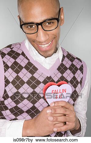 Nerdy man holding a love heart View Large Photo Image Stock Photo - Nerdy man holding a love heart. Fotosearch