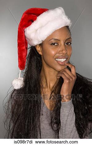 Stock Image - Quizzical woman wearing a santa hat. Fotosearch