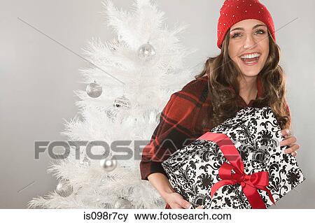 Stock Photo - Smiling woman holding a christmas gift. Fotosearch