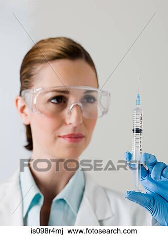 Stock Image - Female scientist holding a syringe. Fotosearch