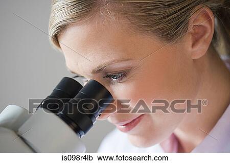 Stock Image - Female scientist using a microscope. Fotosearch