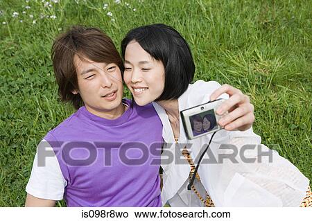Picture - Young couple on field with camera. Fotosearch