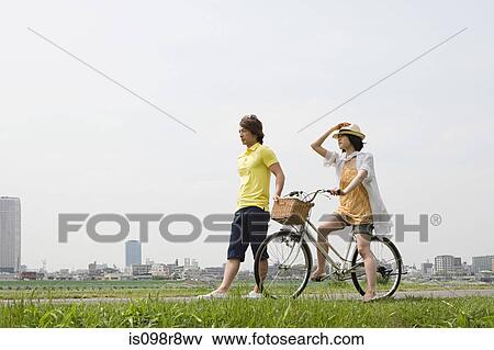 Young man walking and young woman on bicycle View Large Photo Image Stock Photo - Young man walking and young woman on bicycle. Fotosearch