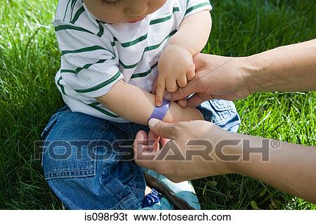 Adult putting plaster on baby boy View Large Photo Image Stock Photograph - Adult putting plaster on baby boy. Fotosearch