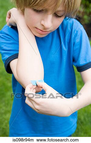 Boy putting plaster on elbow View Large Photo Image Picture - Boy putting plaster on elbow. Fotosearch
