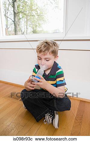 Stock Image - Boy using asthma inhaler with spacer. Fotosearch