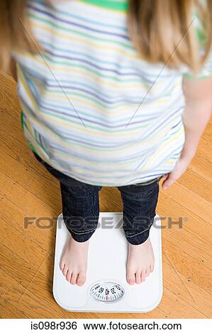 Girl standing on scales View Large Photo Image Stock Photograph - Girl standing on scales. Fotosearch