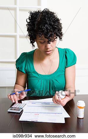 Woman with bills and tablets using calculator View Large Photo Image Picture - Woman with bills and tablets using calculator. Fotosearch