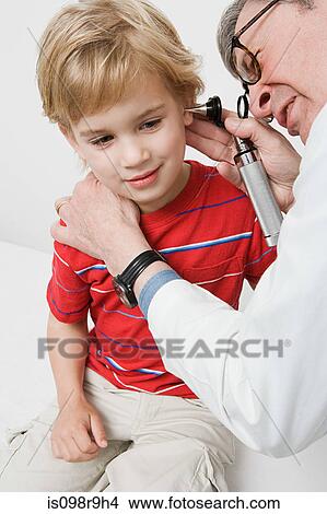Picture - Doctor looking in boys ear. Fotosearch