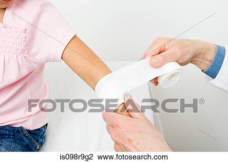 Stock Image - Girl having bandage put on arm. Fotosearch