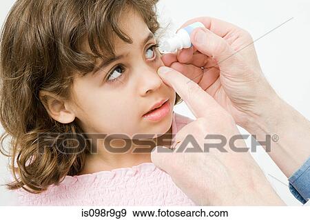 Stock Photo - Girl having eye drops put in. Fotosearch