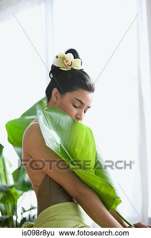 Stock Photograph - Young woman holding a large leaf. Fotosearch