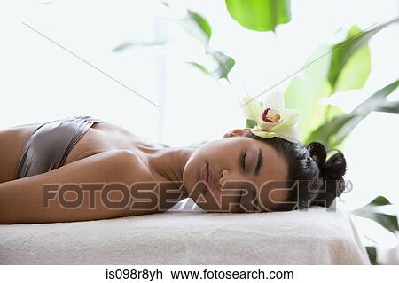 Young woman on massage table with orchid flower in hair View Large Photo Image Stock Image - Young woman on massage table with orchid flower in hair. Fotosearch
