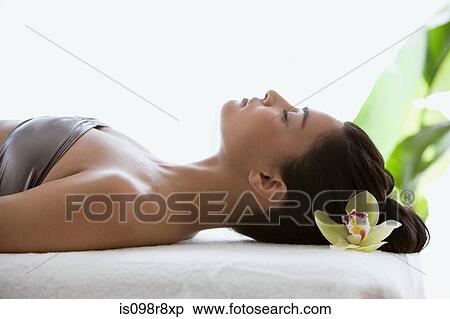 Young woman on massage table with orchid flower in hair View Large Photo Image Stock Photography - Young woman on massage table with orchid flower in hair. Fotosearch
