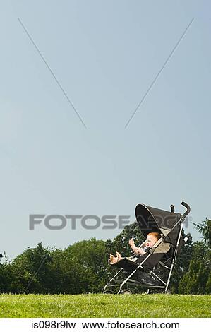 Baby in push chair in park View Large Photo Image Stock Photo - Baby in push chair in park. Fotosearch