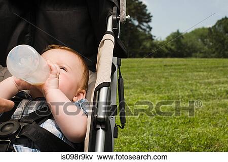 Baby in push chair with bottle View Large Photo Image Stock Photo - Baby in push chair with bottle. Fotosearch