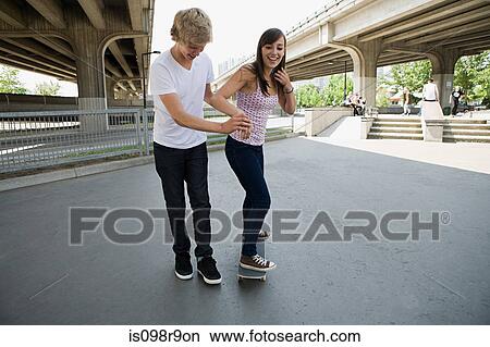 Picture - Boy helping girlfriend to skate. Fotosearch
