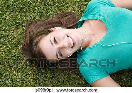 Girl on grass wearing earphones View Large Photo Image Stock Image - Girl on grass wearing earphones. Fotosearch