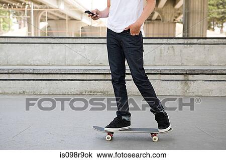 Teenage boy on skateboard with cellphone View Large Photo Image Stock Image - Teenage boy on skateboard with cellphone. Fotosearch